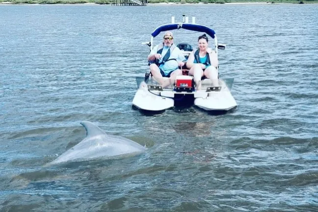 a group of people riding on the back of a boat in the water