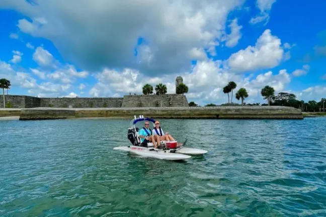 a group of people riding on the back of a boat in the water