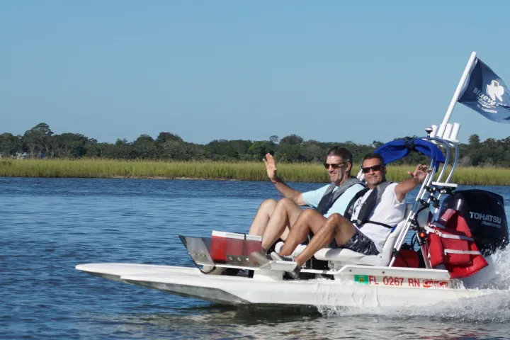 Man and woman waving from catamarn