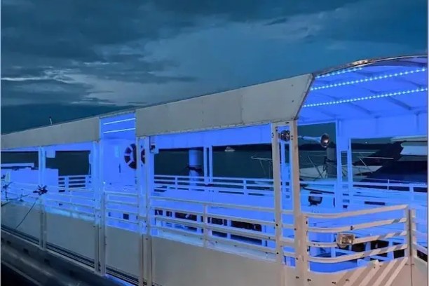 Boat docked at night with blue lighting and 'Bluewater Adventure' text on dark cloudy sky.