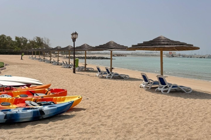 Beach with kayaks, lounge chairs, canopies, and a view of the sea.